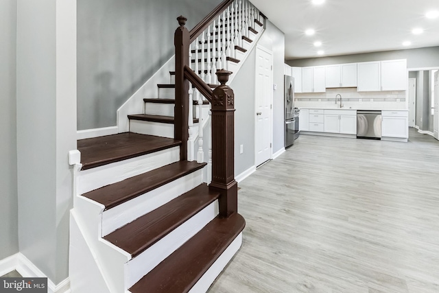 stairs with baseboards, wood finished floors, and recessed lighting