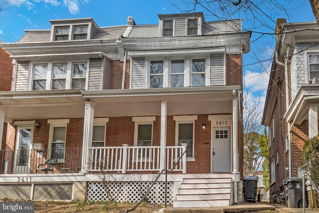 townhome / multi-family property featuring covered porch and brick siding