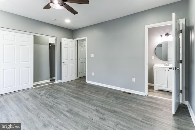 unfurnished bedroom with a closet, wood finished floors, visible vents, and baseboards