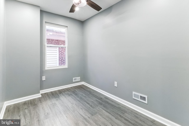 spare room with a ceiling fan, visible vents, baseboards, and wood finished floors