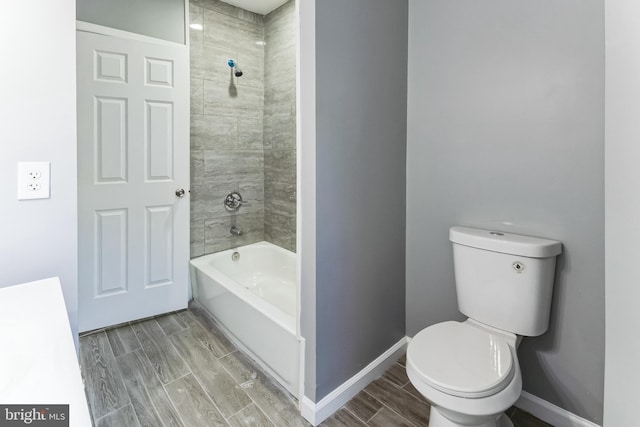 bathroom featuring wood finish floors, baseboards, shower / tub combination, and toilet