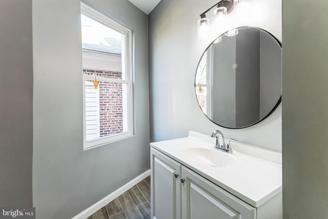 bathroom with plenty of natural light, wood finished floors, vanity, and baseboards