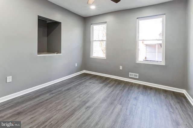 empty room featuring ceiling fan, dark wood-style flooring, visible vents, and baseboards