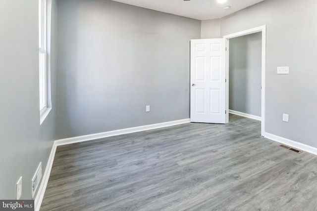 spare room featuring wood finished floors, visible vents, and baseboards