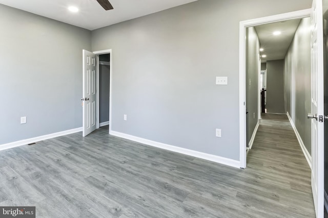 unfurnished bedroom featuring a ceiling fan, visible vents, baseboards, and wood finished floors