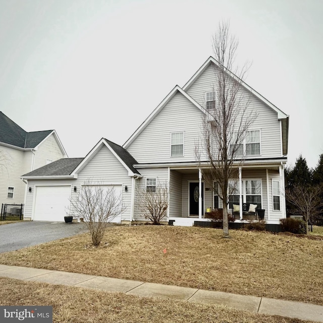 view of property featuring a front yard, a garage, and a porch