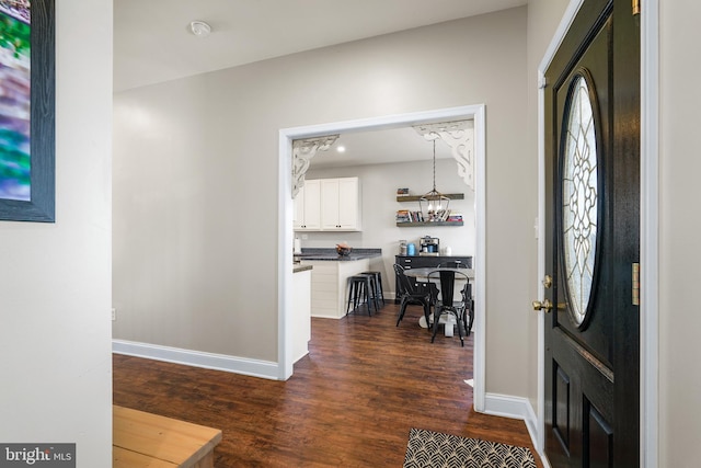 foyer entrance featuring a chandelier and dark wood-type flooring