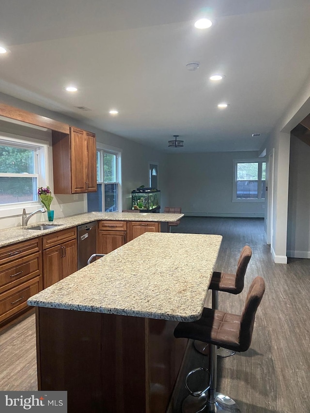 kitchen featuring a breakfast bar, a sink, light wood finished floors, and recessed lighting