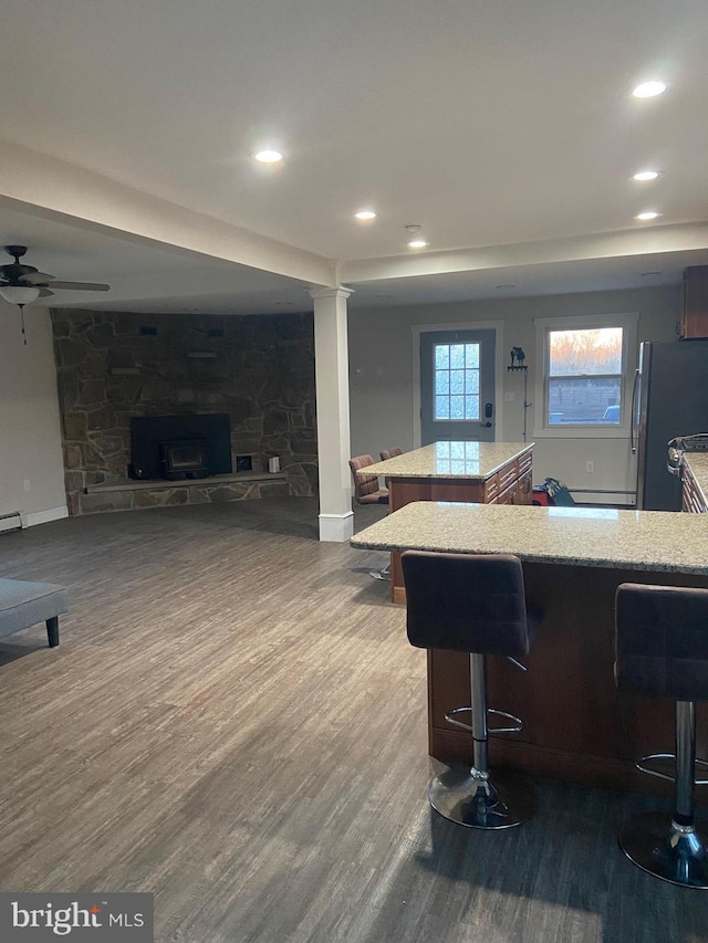 kitchen featuring dark wood-style floors, a breakfast bar area, open floor plan, a center island, and freestanding refrigerator