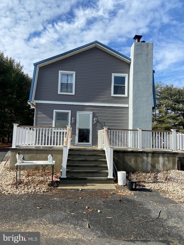 view of front facade featuring stairway, a chimney, and a deck