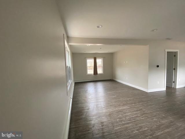 unfurnished room with dark wood-type flooring and baseboards