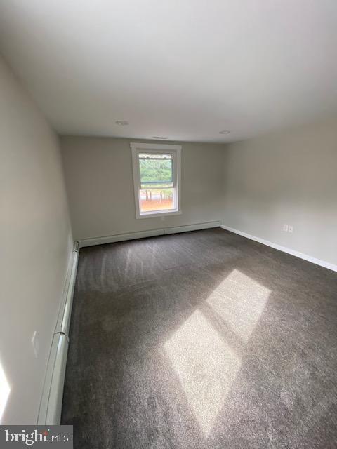 unfurnished room with dark colored carpet and baseboards