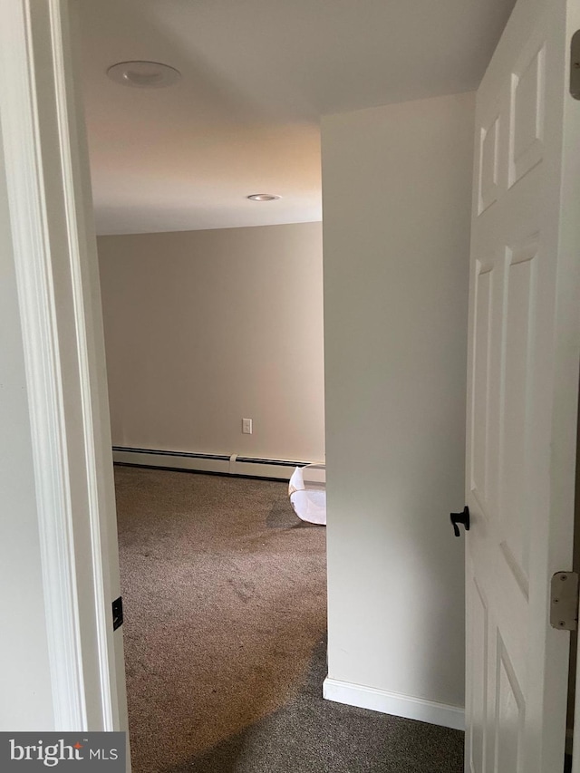 corridor with dark colored carpet, baseboards, and baseboard heating