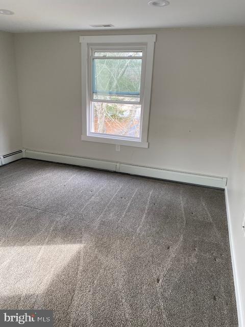 carpeted spare room featuring a baseboard heating unit