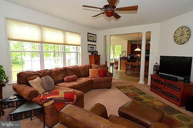 carpeted living room with ornate columns and ceiling fan