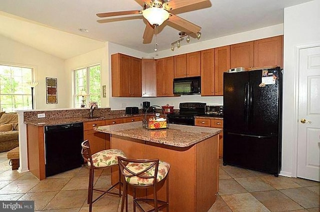 kitchen featuring vaulted ceiling, a breakfast bar, sink, a center island, and black appliances