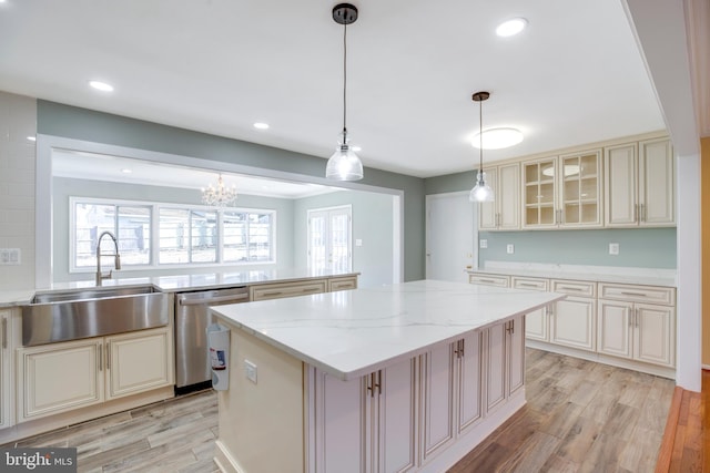 kitchen featuring cream cabinetry, hanging light fixtures, dishwasher, a kitchen island, and sink