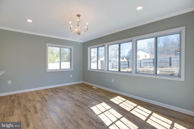 spare room featuring a notable chandelier, wood-type flooring, and ornamental molding