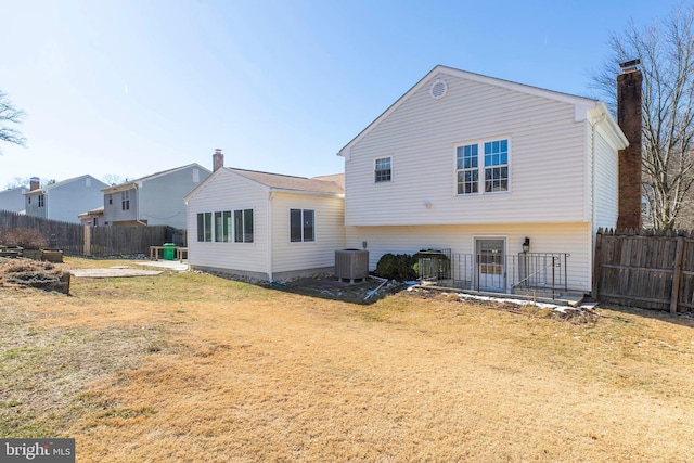 rear view of house featuring central AC and a lawn