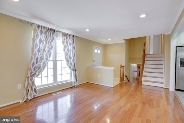 unfurnished living room featuring light wood-type flooring and crown molding