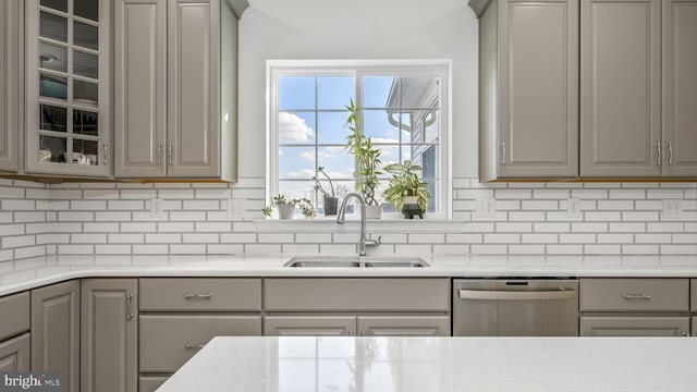 kitchen featuring sink, backsplash, gray cabinets, and dishwasher