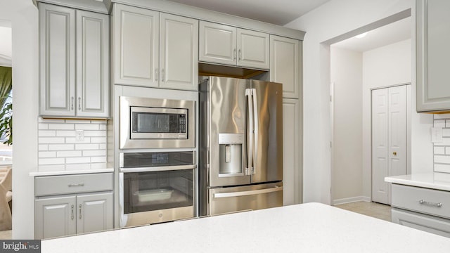 kitchen with appliances with stainless steel finishes, gray cabinetry, and decorative backsplash