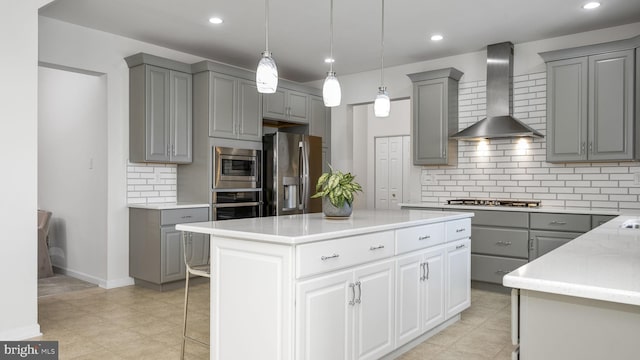 kitchen with gray cabinets, wall chimney range hood, stainless steel appliances, and a center island