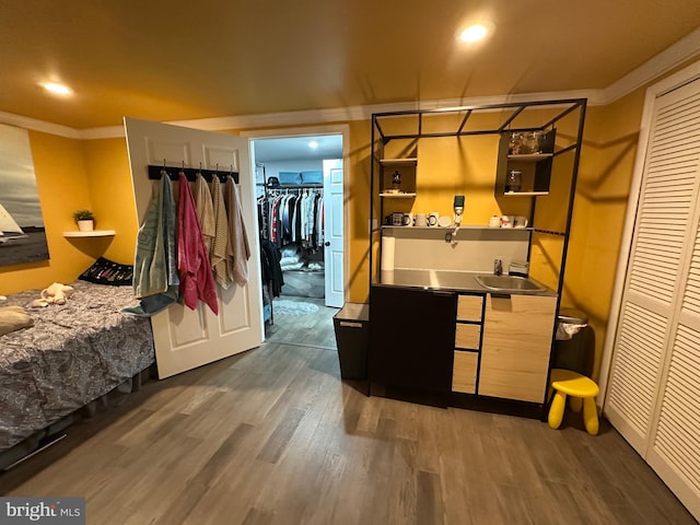 bedroom with ornamental molding, a closet, a sink, and dark wood-type flooring