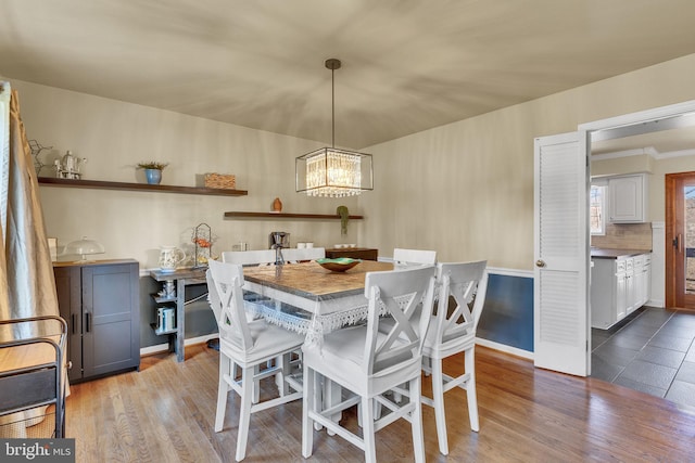 dining area with light wood-type flooring, a notable chandelier, and baseboards