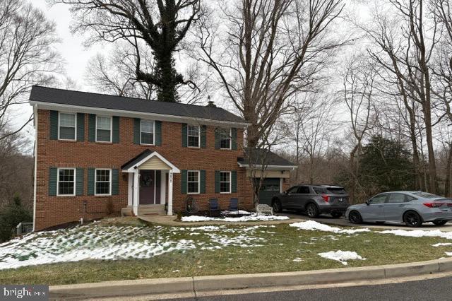 colonial inspired home with brick siding and an attached garage