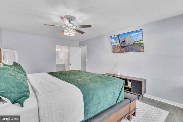 bedroom with baseboards, a ceiling fan, wood finished floors, and ensuite bathroom