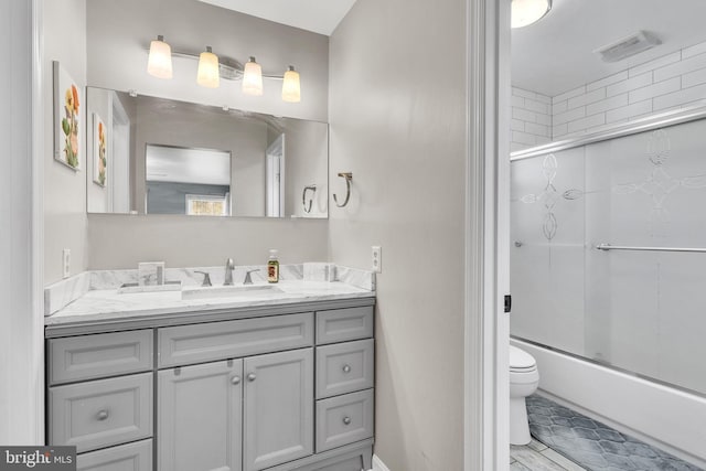 full bathroom with visible vents, vanity, bath / shower combo with glass door, and toilet