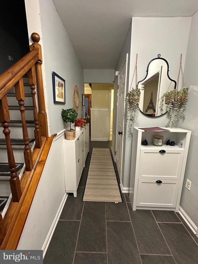 hallway featuring stairway and dark tile patterned flooring