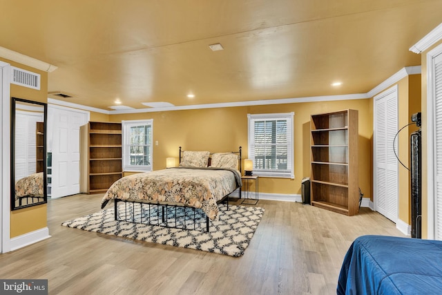 bedroom featuring crown molding, visible vents, light wood-style flooring, and baseboards