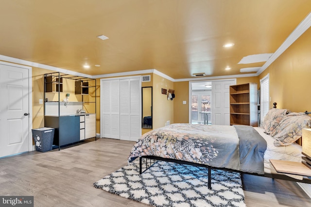 bedroom with wood finished floors, recessed lighting, crown molding, and visible vents