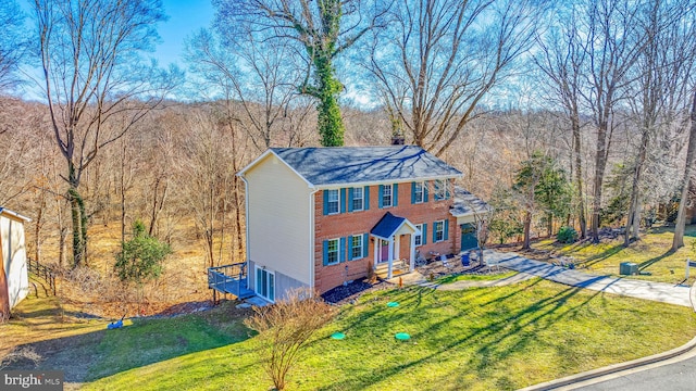 view of front of house featuring a garage, a front yard, a chimney, and brick siding