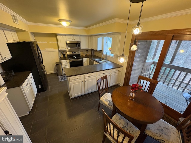 kitchen featuring white cabinetry, dark countertops, hanging light fixtures, and appliances with stainless steel finishes