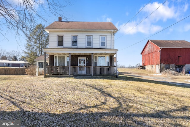 view of front facade featuring a front yard, covered porch, and a storage unit