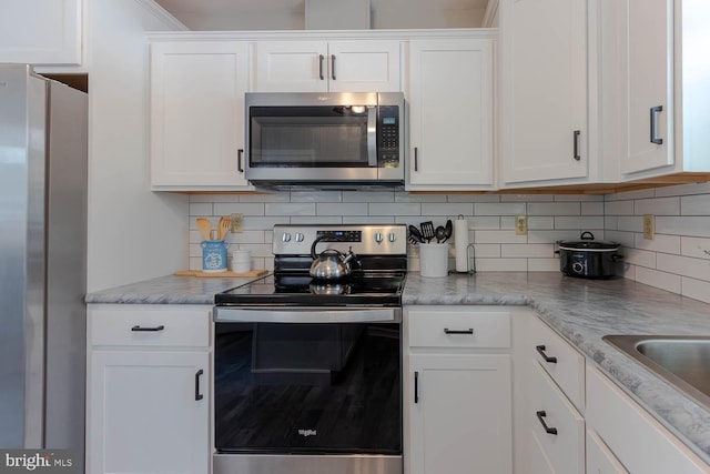 kitchen featuring appliances with stainless steel finishes, tasteful backsplash, light stone counters, and white cabinets