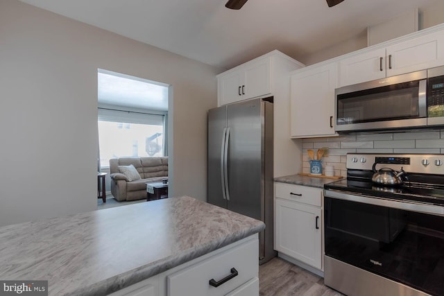 kitchen featuring ceiling fan, stainless steel appliances, white cabinets, and backsplash