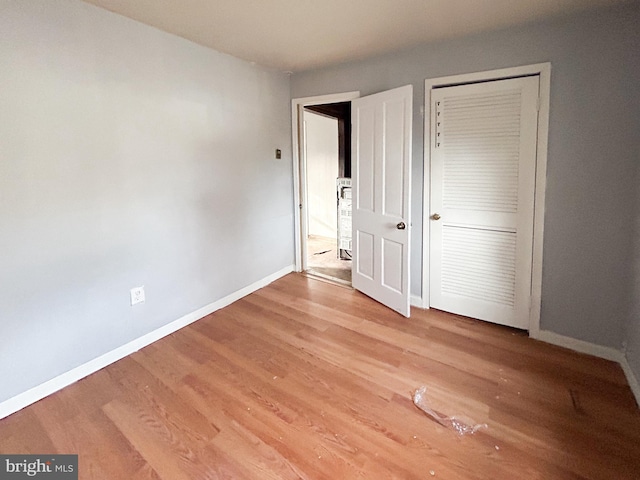 unfurnished bedroom featuring a closet, baseboards, and wood finished floors