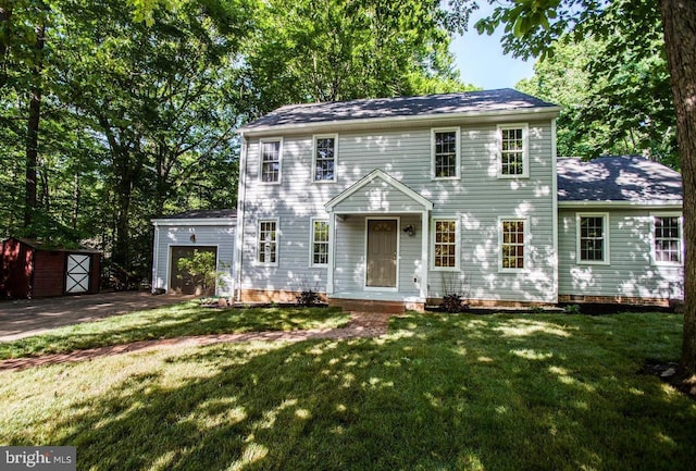 colonial home featuring a garage, a storage shed, and a front lawn