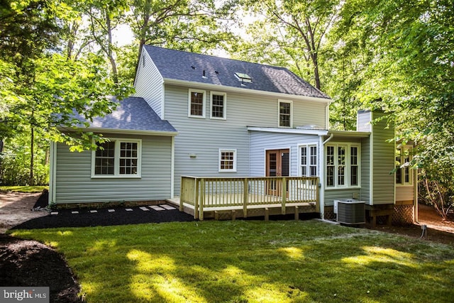 rear view of house with a shingled roof, a lawn, a chimney, a wooden deck, and central AC