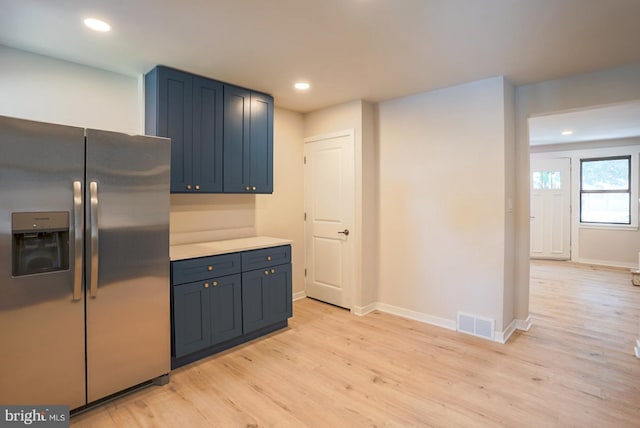 kitchen featuring blue cabinets, stainless steel fridge, and light wood-type flooring