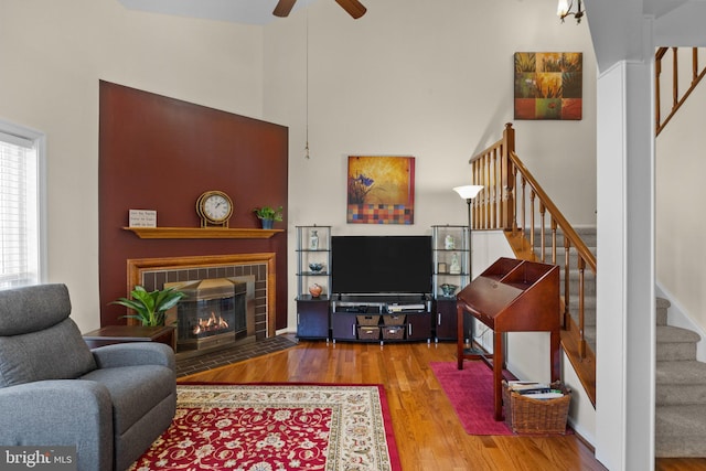 living room with a high ceiling, wood-type flooring, and ceiling fan