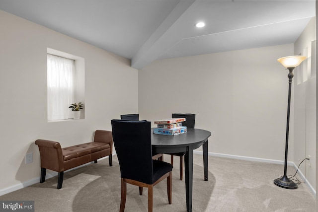 dining space featuring beamed ceiling and light carpet