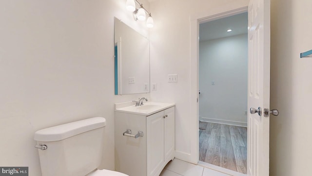 bathroom with toilet, tile patterned flooring, baseboards, and vanity