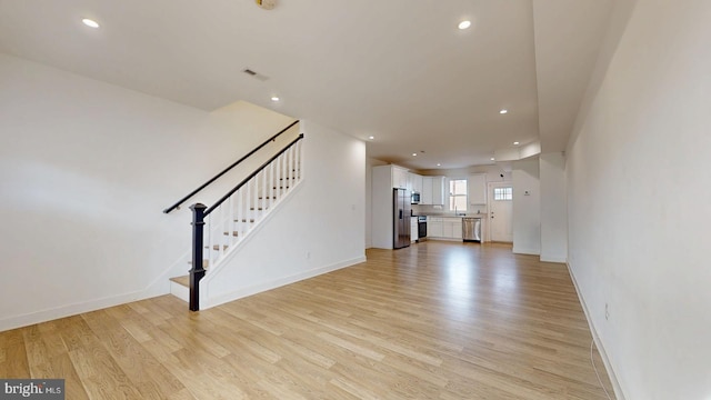 unfurnished living room with light wood-type flooring, stairway, baseboards, and recessed lighting