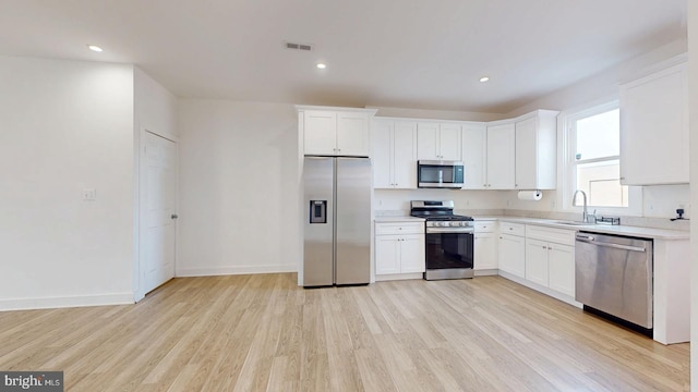 kitchen with light countertops, appliances with stainless steel finishes, a sink, and visible vents