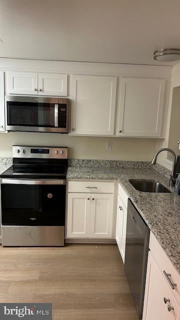 kitchen with sink, stainless steel appliances, white cabinets, and light stone countertops